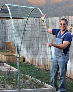 a man in overalls and an apron standing next to a garden trellis