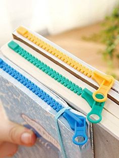 a person holding an open book with legos attached to the pages and scissors on top