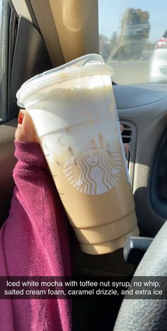 a cup of coffee sitting on top of a car seat next to a person's arm