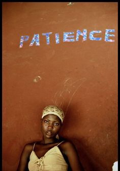 a woman standing in front of a wall with the word patience written on it