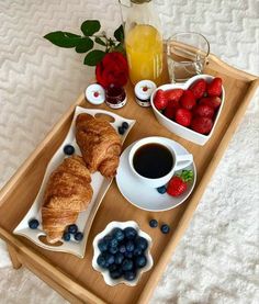 a breakfast tray with croissants, berries and coffee