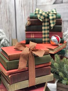 a stack of books with a bow tied around them on top of each other next to small christmas trees