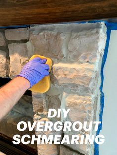 a person in blue gloves is cleaning a brick fireplace with a sponge and cloth on it