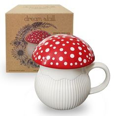 a red and white mushroom shaped coffee mug next to a box