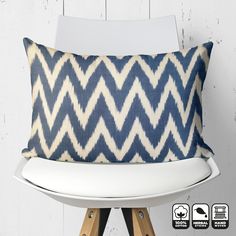 a blue and white pillow sitting on top of a wooden chair next to a white wall