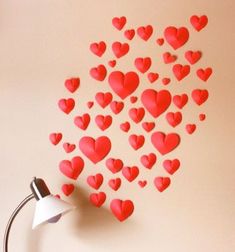 a lamp and some red hearts on a white wall in the shape of a heart