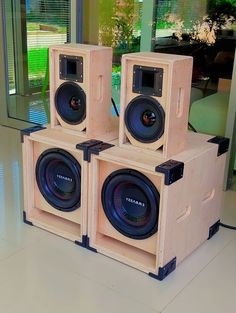 three wooden speakers sitting on top of each other in front of a glass door and window