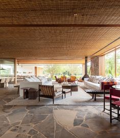 a living room filled with furniture next to a stone covered floor and windows overlooking the outdoors