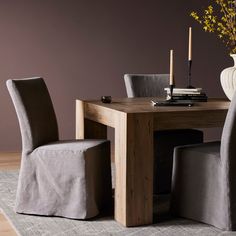 a wooden table with two chairs and a vase on top of it next to a rug