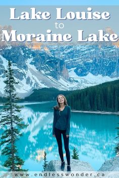 a woman standing on top of a rock next to a lake with mountains in the background