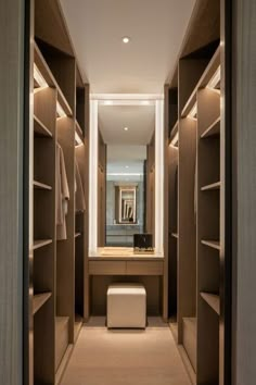 a walk in closet with lots of wooden shelves and lights on the wall above it