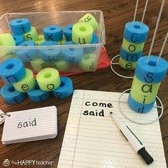 some blue and green letters are on the table next to a pen, paper with writing