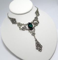 This is a new handmade necklace. It is made with antiqued silver plated filigrees, accented with a high quality EMERALD GREEN glass rhinestone. Decorated portion is 6" wide and 3 1/4" tall in the center. Necklace is adjustable 15-18" with a lobster clasp and chain extender. If you would like a different length, please send us a message. Gothic Metal Necklace With Intricate Design, Gothic Filigree Necklace For Wedding, Gothic Wedding Necklace With Filigree Detail, Gothic Filigree Wedding Necklace, Gothic Metal Jewelry With Filigree, Gothic Antique Silver Jewelry With Intricate Design, Gothic Filigree Metal Jewelry, Antique Silver Victorian Metal Necklace, Victorian Antique Silver Necklace