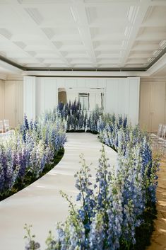 a wedding ceremony with blue and white flowers on the aisle