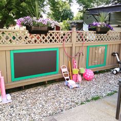 there is a chalkboard on the side of this fence and some toys are in front of it