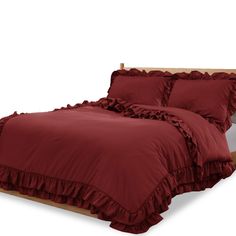 a bed with red ruffles and pillows on it's headboard, in front of a white background