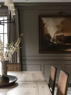 a dining room table with flowers in a vase on the top and chairs around it