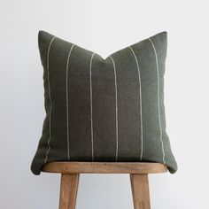 a green and white striped pillow sitting on top of a wooden stool