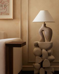 a lamp sitting on top of a table next to a white couch in a living room