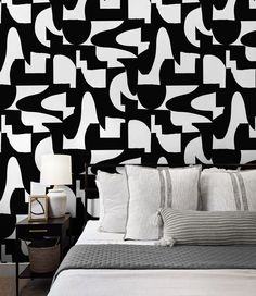 a bedroom with black and white wallpaper that has geometric shapes on it, along with a bed