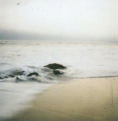 an ocean with waves coming in to shore and a rock sticking out of the water