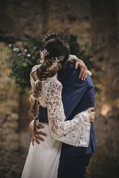 a bride and groom embracing each other in front of a stone wall