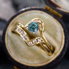 a gold ring with a blue stone in it sitting on top of a velvet case