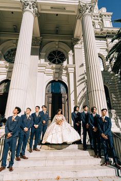 a bride and groom standing on the steps of a building with their bridal party