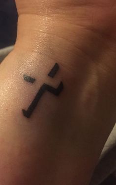 a small black cross tattoo on the wrist