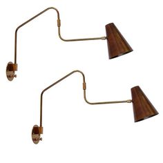 two brass wall lights with wooden shades on each lamp arm and one light has a brown shade