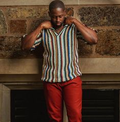 a man standing in front of a brick wall with his hands on his hips and arms behind his head