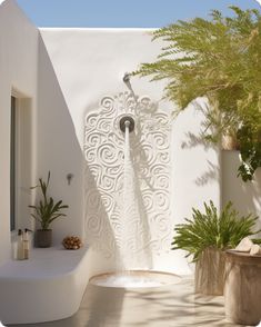 an outdoor shower in the middle of a patio with potted plants on either side