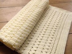 a white crocheted blanket sitting on top of a wooden floor next to a table