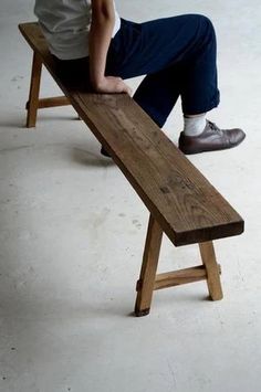 a man sitting on a wooden bench with his feet propped up against the backrest