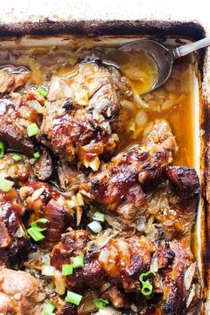 an image of meat with onions and gravy in a baking dish on a table