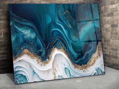 an abstract painting with blue and white colors on the wall next to a brick wall