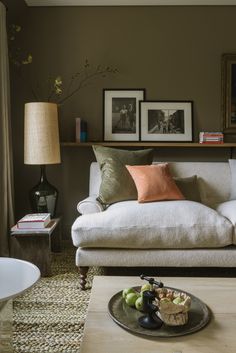 a living room with a white couch and coffee table in front of a painting on the wall