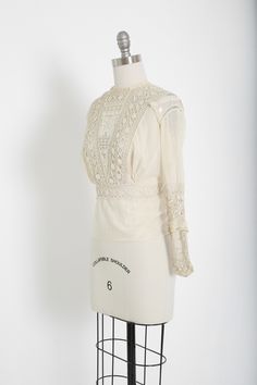 "Stunning Antique vintage early 1900's Edwardian crochet blouse Floral embroidered crochet lace, high neck long sleeve Natural cotton in ivory / cream button down back Great vintage condition - few age spots (see photos) very wearable M e a s u r e m e n t s: Size: fits like a XS S BUST: 18 1/2\" Waist: 13\" Total Length: 22\" Sleeves: 20\" Label: unbranded Fabric: cotton +All Measurements are taking while garment is lying flat+ + Jewelry, belts, and any other accessories are NOT included unless Victorian Long Sleeve Tops For Spring, Classic Lace Tops With Lace Sleeves, Vintage Blouse With Lace Sleeves, Classic Lace Tops With Lace Work, Elegant Cream Top With Crochet Lace, Elegant Cotton Lace Daywear Top, Formal Long Sleeve Lace Top With Lace Trim, Elegant Cream Crochet Lace Top, Elegant Long Sleeve Blouse With Crochet Lace