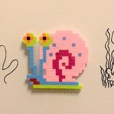 a piece of art made out of legos on a wall next to a drawing of a snail