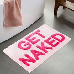 a bathroom rug that says get naked on the floor next to a bathtub and toilet