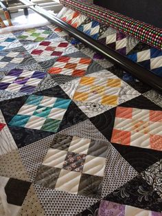 a close up of a quilt on a bed with an ironing board in the background