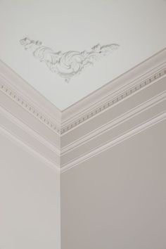 the corner of a room with a white ceiling and decorative molding on the walls