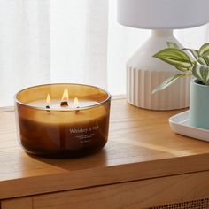 a candle sitting on top of a table next to a potted plant