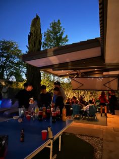 people are sitting at an outdoor table with drinks in front of them and on the other side