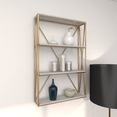 a shelf with vases and other items on it next to a wall mounted lamp