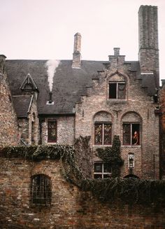 an old brick building with ivy growing on it's sides and windows in the front