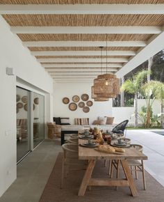 an outdoor dining area next to a swimming pool with wicker hanging from the ceiling