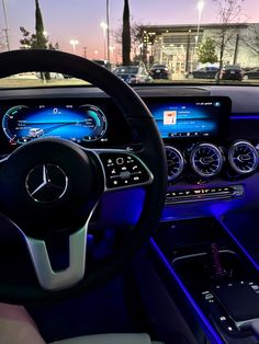 the interior of a car with illuminated dashboard and steering wheel, along with blue lights