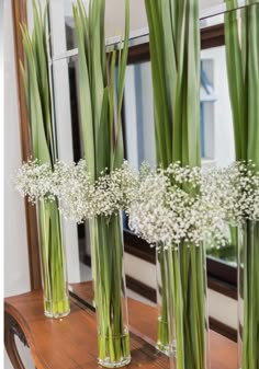 three clear vases filled with baby's breath flowers on top of a wooden table