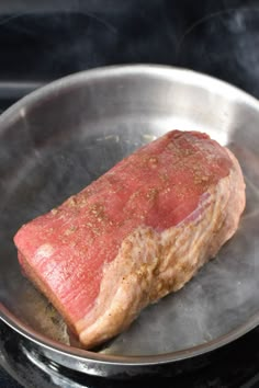 a piece of meat is cooking in a frying pan